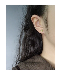 Detailed view of gold minimalist spiral textured round stud earrings on a female model