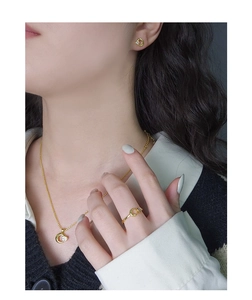 Dettaglio di un set di gioielli in oro minimalista con zirconi a cuore indossato da modella