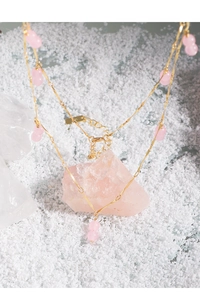 Detail view of a gold twisted chain necklace with pink agate gourd charms on pink stones