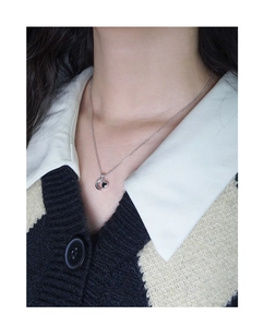 Dettaglio della collana con ciondolo luna e cuore indossata su maglieria elegante