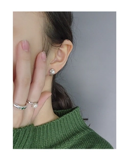 Détail d'un mannequin portant des boucles d'oreilles perles et des bagues assorties