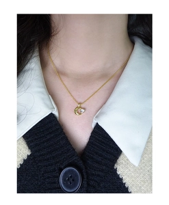 Primo piano di una collana dorata con pendente a luna e cuore su una modella