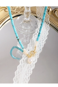 Dettaglio della collana barocca in turchese blu con perle e chiusura a levetta dorata