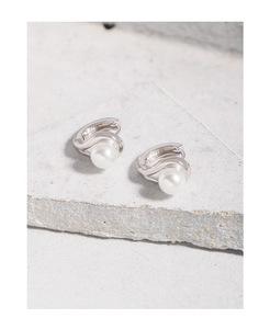 Gros plan de boucles d'oreilles argentées minimalistes avec perles sur socle en pierre