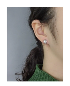 Gros plan d'une boucle d'oreille minimaliste en perle avec base argentée sur modèle