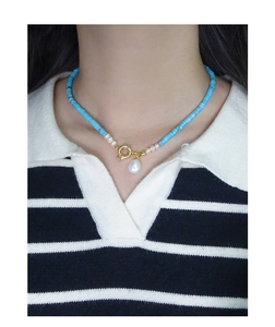 Collana con ciondolo in perla barocca, perline turchesi e chiusura dorata su una modella