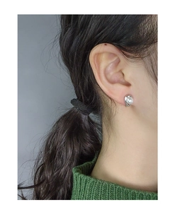 Vue détaillée d'une boucle d'oreille argentée en spirale avec perle portée sur l'oreille