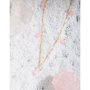 Elegant gold necklace with pink agate double beads over aesthetic crystal background