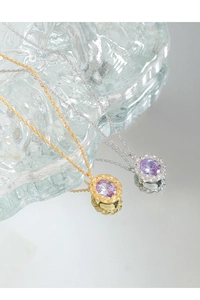 Detail of twisted metal bezel necklace with oval purple zircon in gold and silver finish