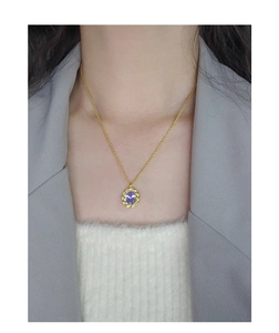 Detail of a 925 silver twist pendant with a purple zircon stone on a golden chain