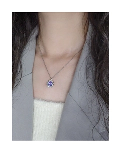 Detail of twisted silver necklace with purple zircon pendant worn on a female model