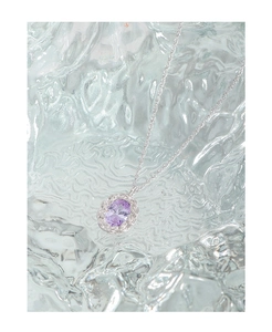 Macro detail of twisted silver pendant with oval purple zircon on textured ice glass background