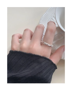 Detailansicht eines silbernen Rankenrings mit gedrehter Metallstruktur am Finger