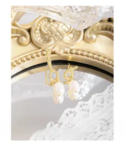 Detailed close-up of Baroque pearl earrings with irregular gold plating on lace