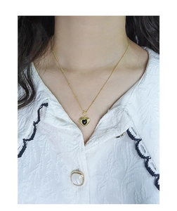 Nahaufnahme der goldenen Herz-Halskette mit schwarzem Achat-Anhänger am Model