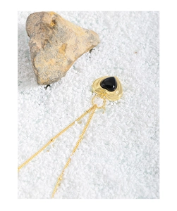 Detailansicht der Vintage Gold-Herz-Halskette mit schwarzem Achat auf Sandhintergrund