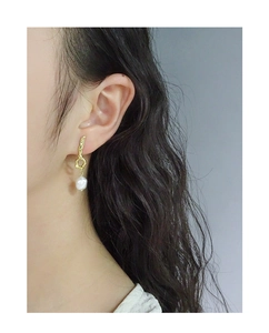 Close-up of silver baroque pearl earrings with irregular hammered gold texture on model