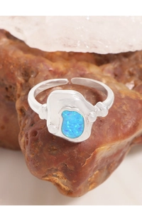 Détail d'une bague en argent irrégulière avec opale bleue sur cristaux naturels