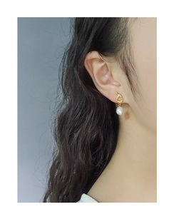 Detail of baroque pearl earring with irregular gold hoop shown on model