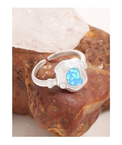Gros plan d'une bague en argent S925 avec opale bleue irrégulière et détails perlés
