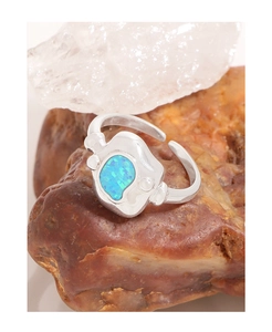 Gros plan d'une bague en argent S925 avec opale bleue irrégulière sur pierre brute
