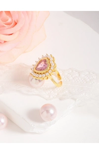 Vue détaillée bague dorée avec pierre rose en cœur et bordure de petites perles