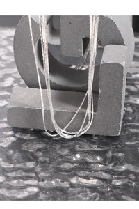 Detail of layered S925 sterling silver necklaces displayed on stone geometric props