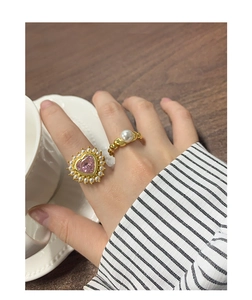 Détail de bagues serties de zircons cœurs roses et perles sur anneaux dorés vintage