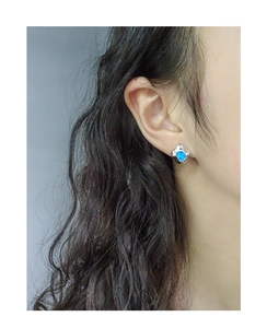 Macro view of irregular blue opal stud earring on ear with polished S925 silver finish