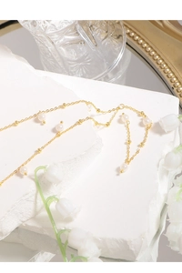 Detailed close-up of a gold S925 silver Y-shaped pearl necklace on a white stone background