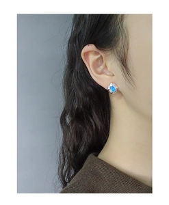 Detail of S925 silver stud earring with ocean blue opal stone on a model ear