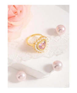 Vue détaillée de la bague en forme de cœur avec pierre rose et perles sur dentelle
