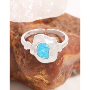 Bague irrégulière en argent 925 avec opale bleue naturelle posée sur une roche brute