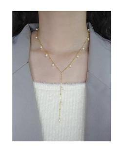 Elegant 18K gold Y-shaped pearl necklace on a model wearing a grey blazer