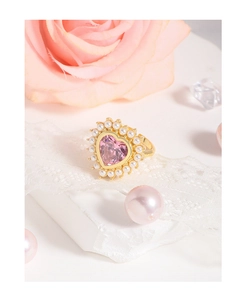 Détail de la bague coeur en zircon rose avec perles blanches sur fond de dentelle