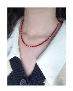Detail of red synthetic coral and S925 silver beaded necklace worn on neck