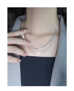 Detail view of tiered S925 sterling silver layered necklace chains on model neck