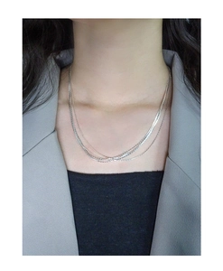 Detail shot of multilayered silver necklaces in varied textures on a female model
