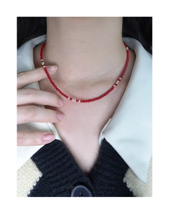 Detail shot of dainty red beaded choker necklace with silver spacers on a female model