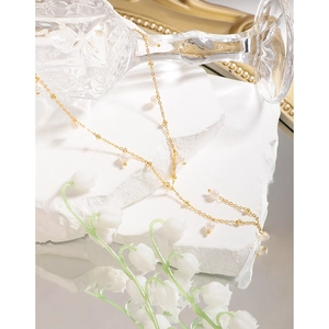 Elegant gold Y-shaped S925 silver necklace with white pearls on a minimalist stone base