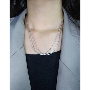 Elegant silver-toned multi-layered layered necklace on female model in grey suit