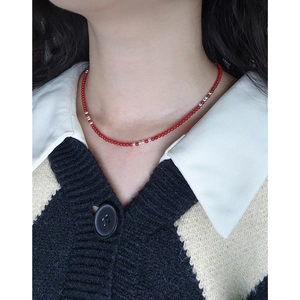 Elegant S925 silver necklace with red coral beads worn by a woman over a white shirt