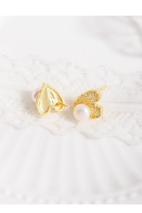 Macro shot of gold heart stud earring with hammered texture and white pearl detail