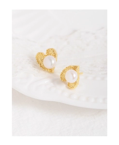 Detail view of heart-shaped gold studs with hammered texture and white pearls