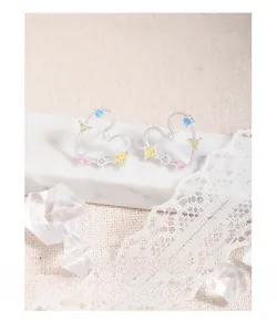 Detailed shot of rainbow zircon heart earrings on marble stand with elegant lace