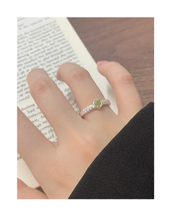 Detail of silver heart ring with green gemstone on textured band and vintage book