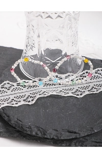Detail of silver beaded bracelet with colorful crystals on a dark stone background