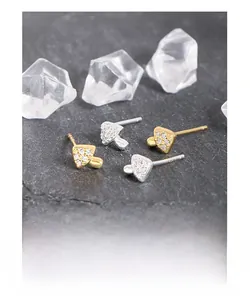 Macro shot of silver and gold mushroom stud earrings with cubic zirconia on stone background