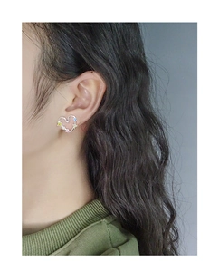 Close-up of S925 silver hollow heart earrings with colorful rainbow zircons on ear