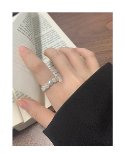 Nahaufnahme des S925 Silberherzrings mit Zirkonia auf einer Hand über einem Buch